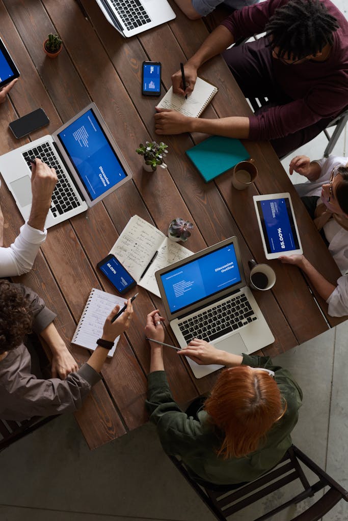 A diverse group of professionals brainstorming with laptops and notepads in a modern office.