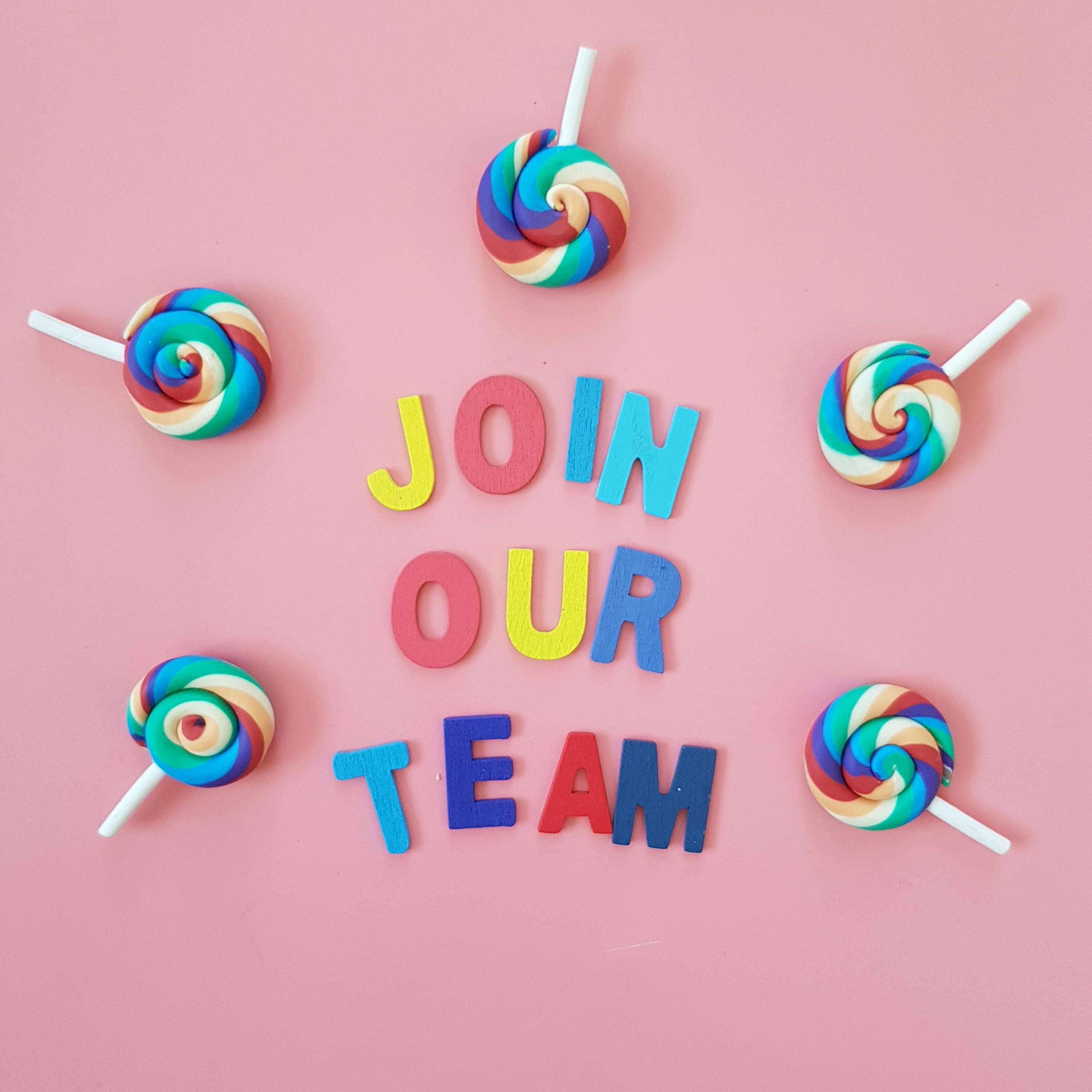 Vibrant Join Our Team message surrounded by colorful lollipops on pink background.